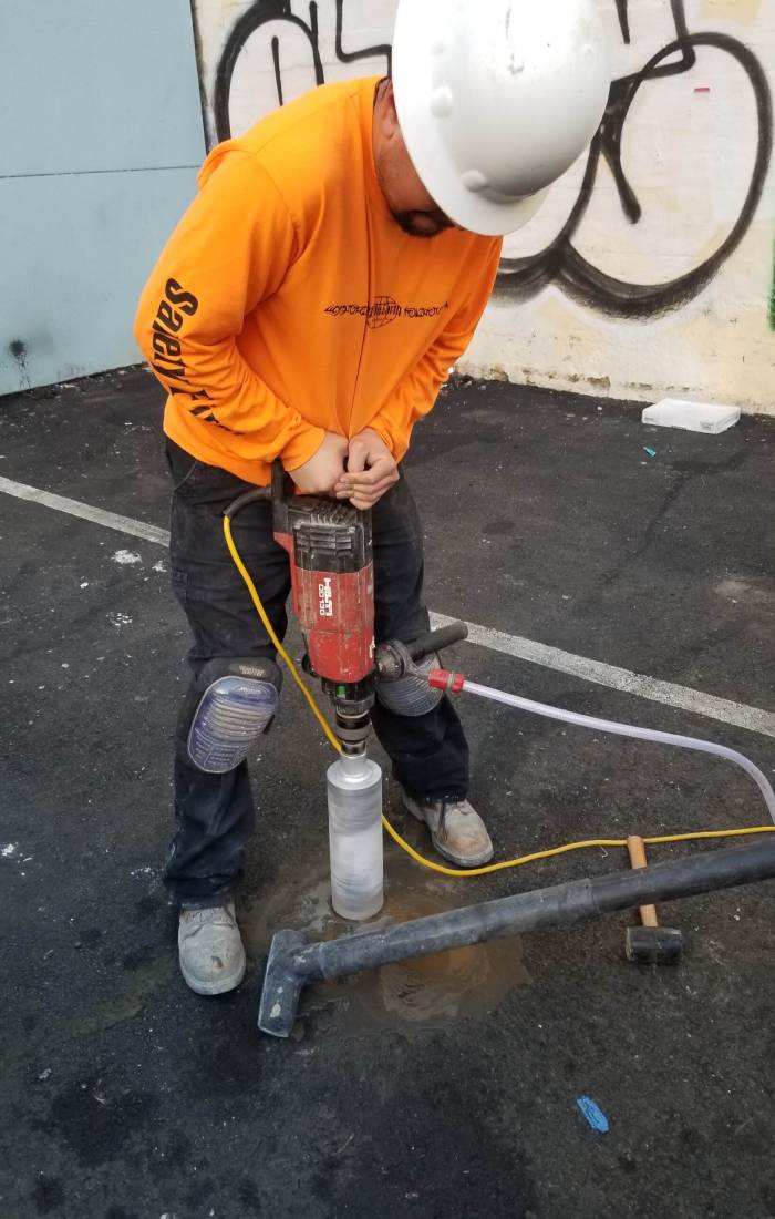 A man in an orange shirt is using a drill